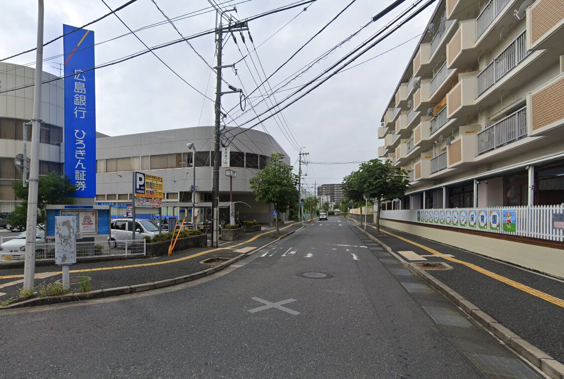 大通りに面した銀行の看板とその隣にある駐車場、並んだ建物。