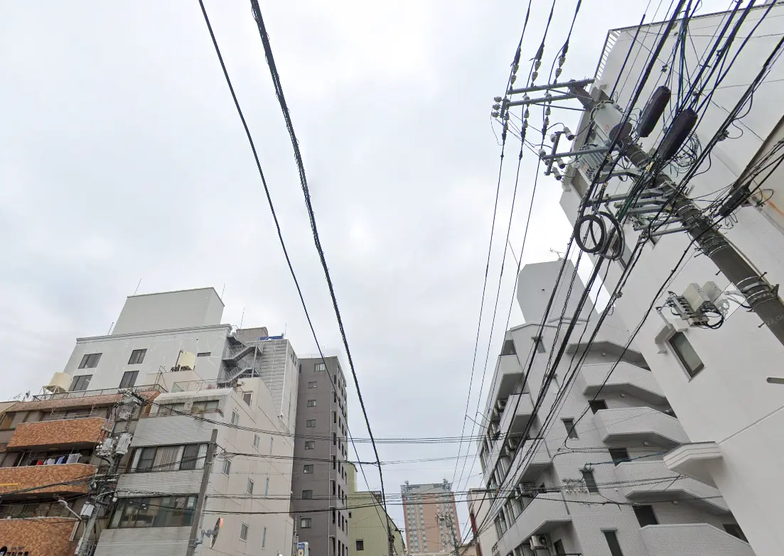 都市の電線と建物が見える曇り空の風景