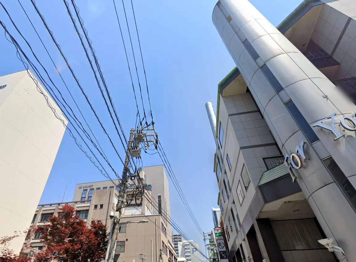 ビルと電柱が立ち並ぶ、青空の広がる市街地の風景。